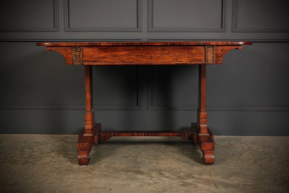A Regency rosewood library writing table with rounded corners, carved trestle supports, a low stretcher, and scrolled feet. View III