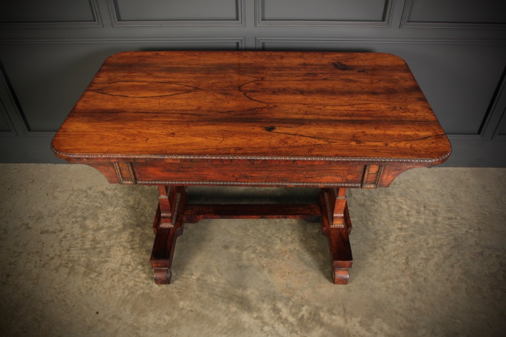 A Regency rosewood library writing table with rounded corners, carved trestle supports, a low stretcher, and scrolled feet. View XII