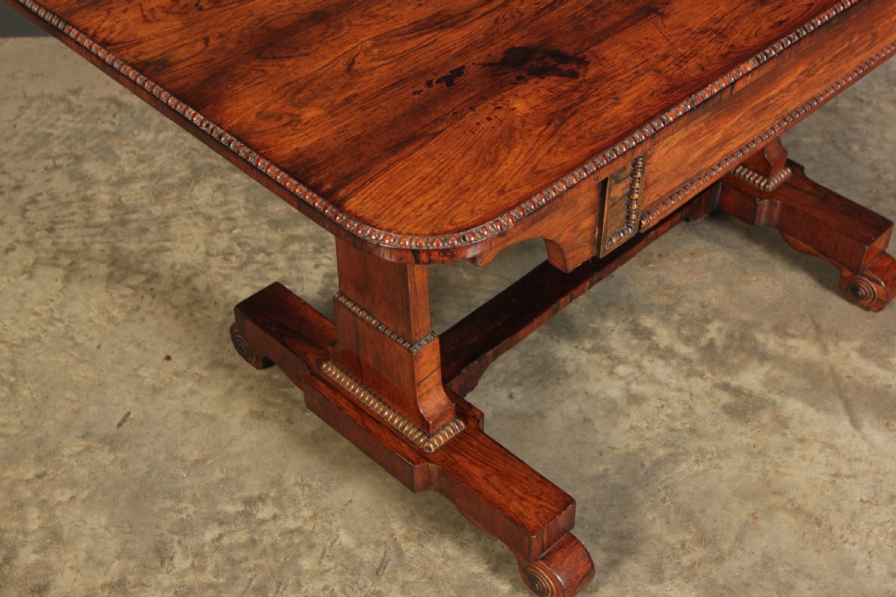 A Regency rosewood library writing table with rounded corners, carved trestle supports, a low stretcher, and scrolled feet. View XIII