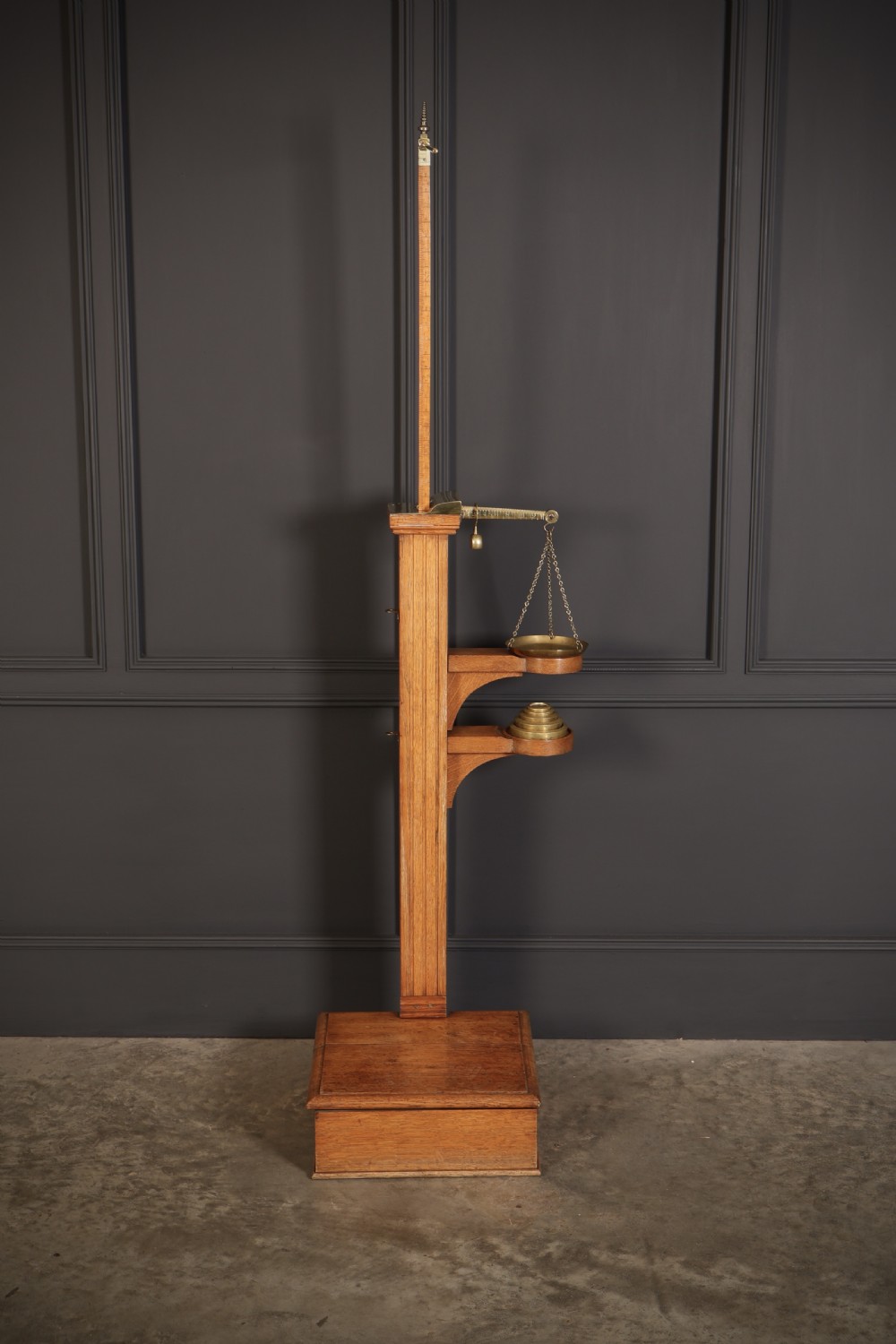 Victorian floor-standing personal weighing scales crafted from oak with brass fittings, balance arm, pan, stacked weights, and a wooden base platform. View III