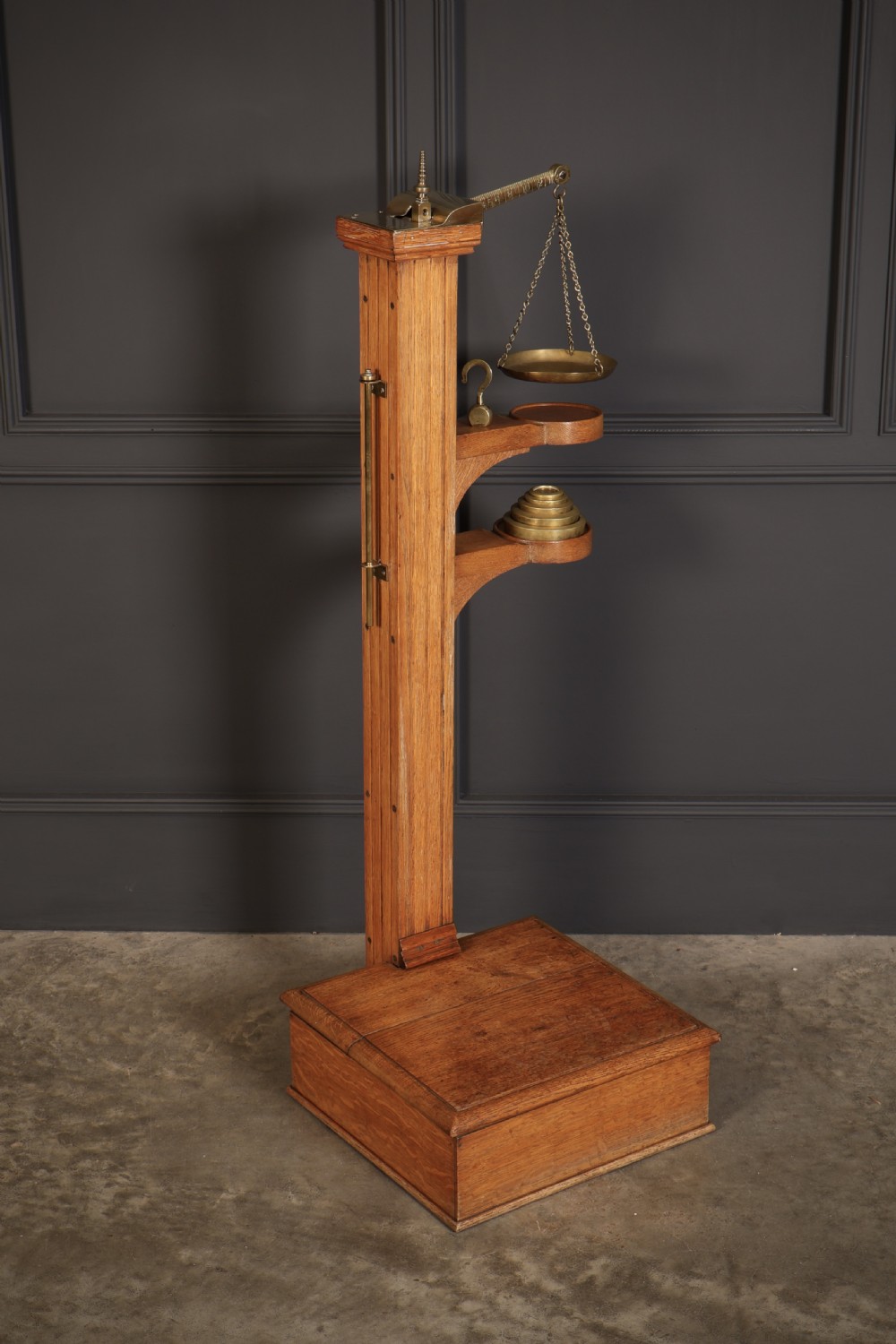 Victorian floor-standing personal weighing scales crafted from oak with brass fittings, balance arm, pan, stacked weights, and a wooden base platform. View V