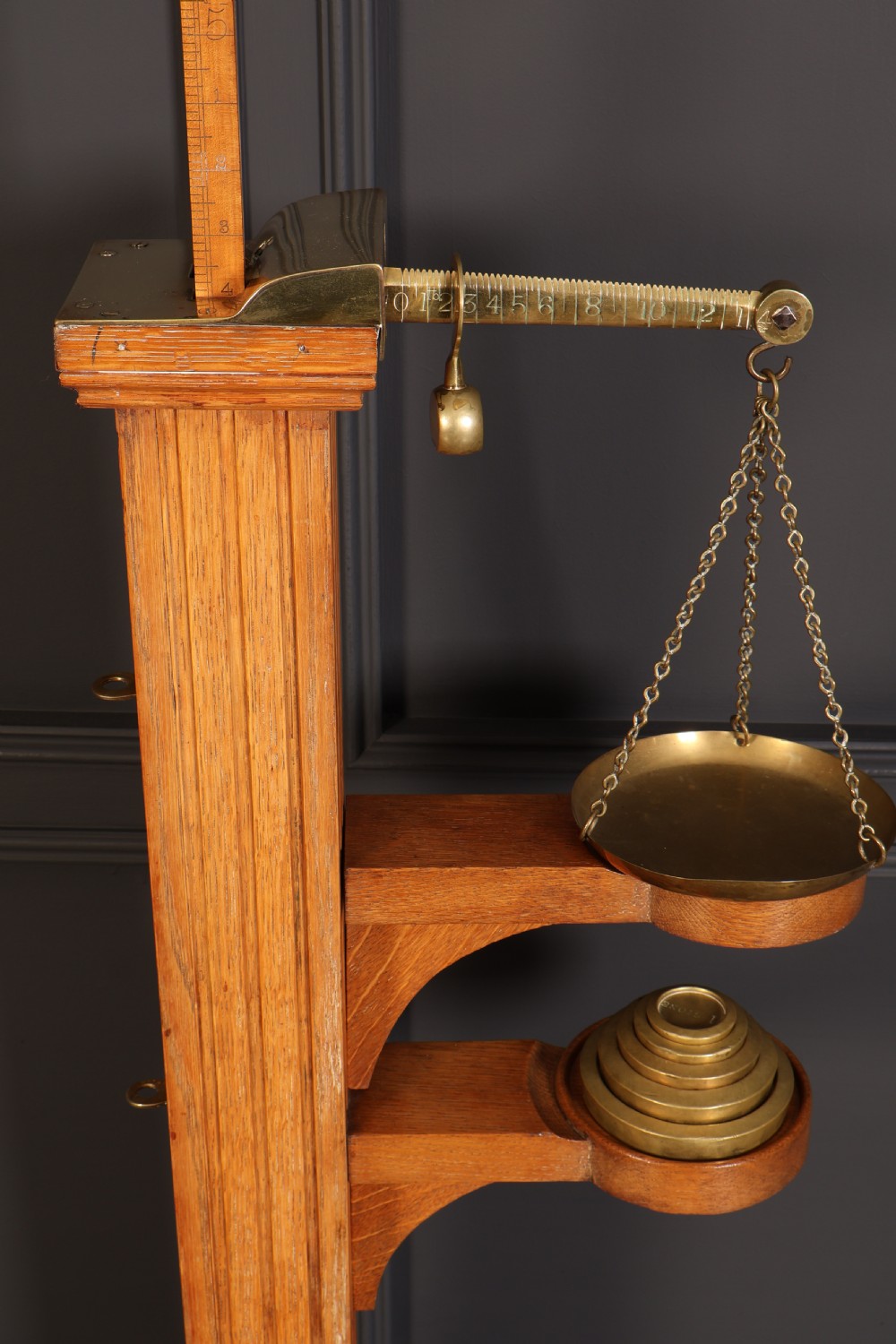Victorian floor-standing personal weighing scales crafted from oak with brass fittings, balance arm, pan, stacked weights, and a wooden base platform. View VII