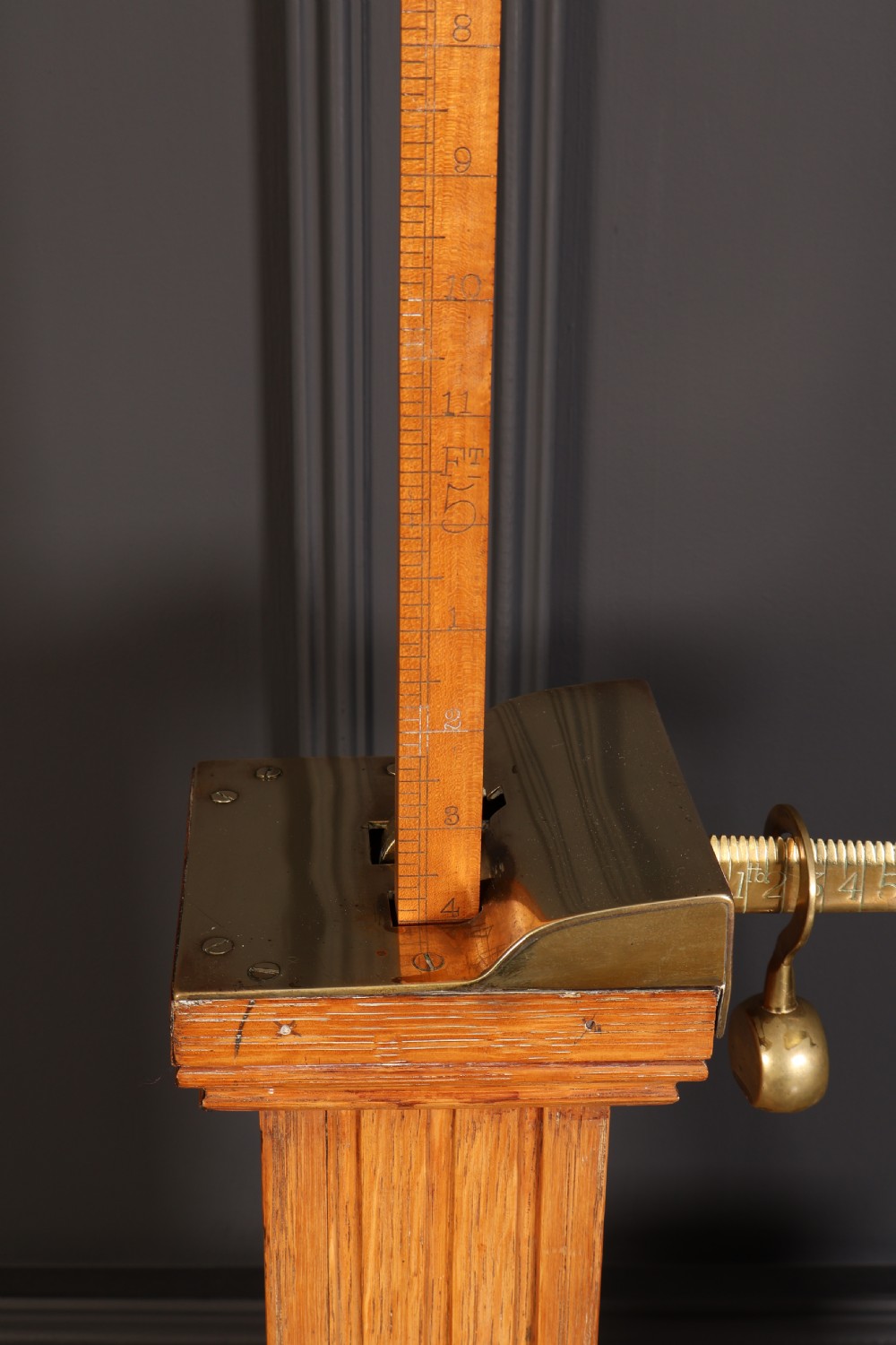 Victorian floor-standing personal weighing scales crafted from oak with brass fittings, balance arm, pan, stacked weights, and a wooden base platform. View VIII