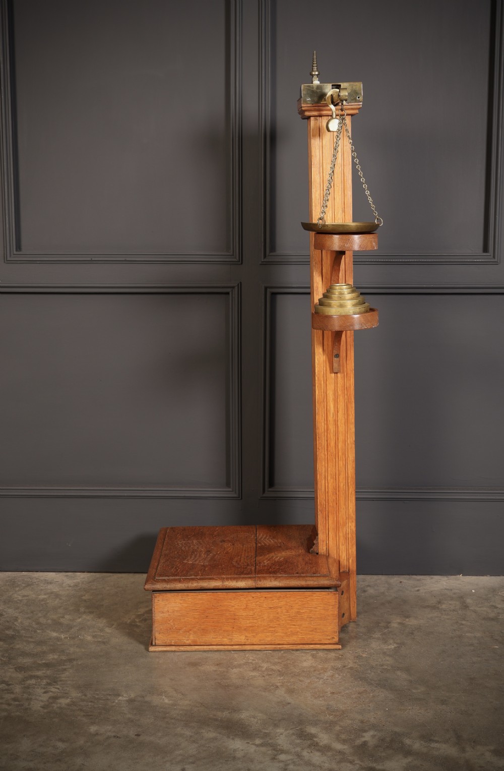 Victorian floor-standing personal weighing scales crafted from oak with brass fittings, balance arm, pan, stacked weights, and a wooden base platform. View X