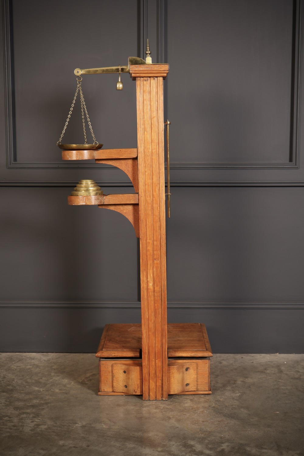 Victorian floor-standing personal weighing scales crafted from oak with brass fittings, balance arm, pan, stacked weights, and a wooden base platform. View XI