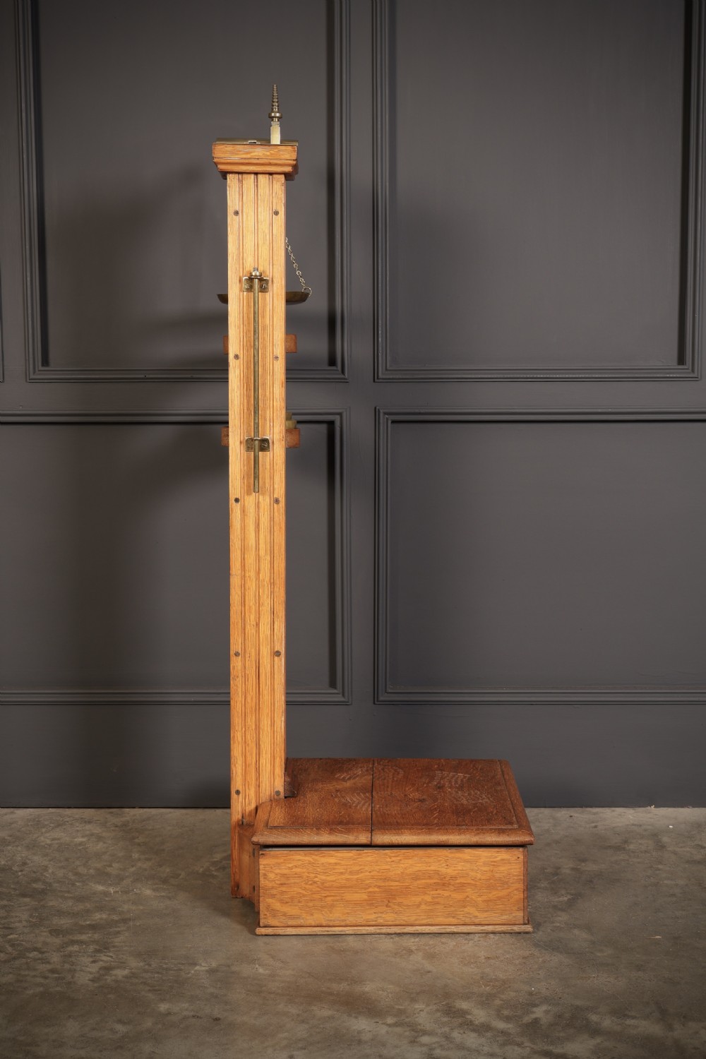 Victorian floor-standing personal weighing scales crafted from oak with brass fittings, balance arm, pan, stacked weights, and a wooden base platform. View XII