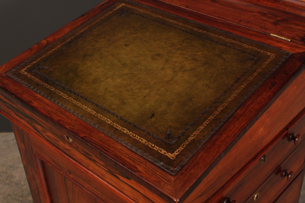A William IV rosewood Davenport desk featuring a green leather sloped writing surface, side drawers with wooden knob handles, and turned feet on brass castors. View VIII
