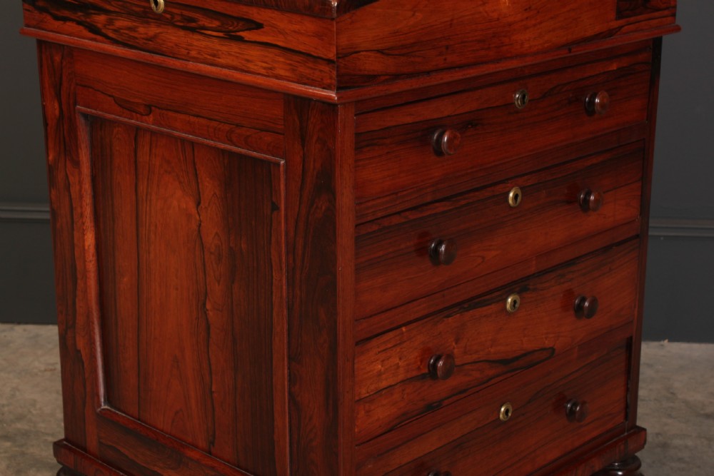 A William IV rosewood Davenport desk featuring a green leather sloped writing surface, side drawers with wooden knob handles, and turned feet on brass castors. View IX