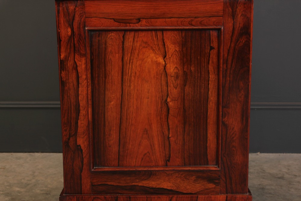 A William IV rosewood Davenport desk featuring a green leather sloped writing surface, side drawers with wooden knob handles, and turned feet on brass castors. View XIV