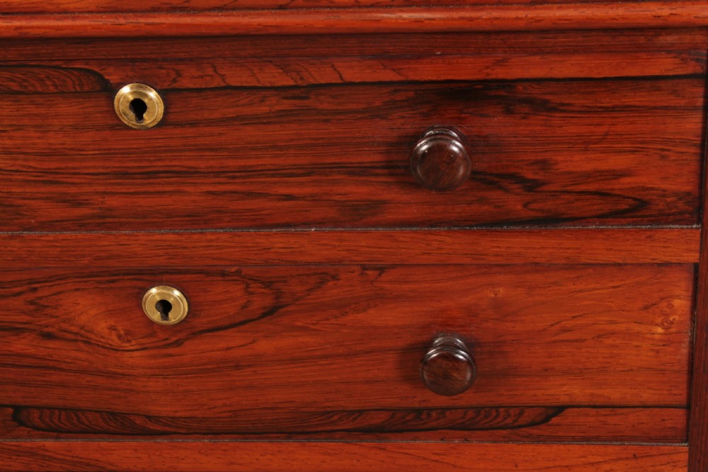 A William IV rosewood Davenport desk featuring a green leather sloped writing surface, side drawers with wooden knob handles, and turned feet on brass castors. View XIX