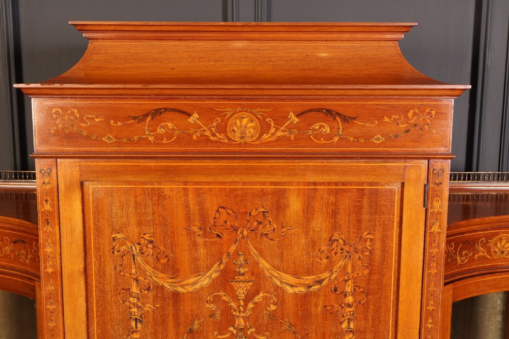 An Edwardian mahogany side cabinet with a central door featuring an urn marquetry inlay, flanked by two curved glazed display sections on tapered legs. View V