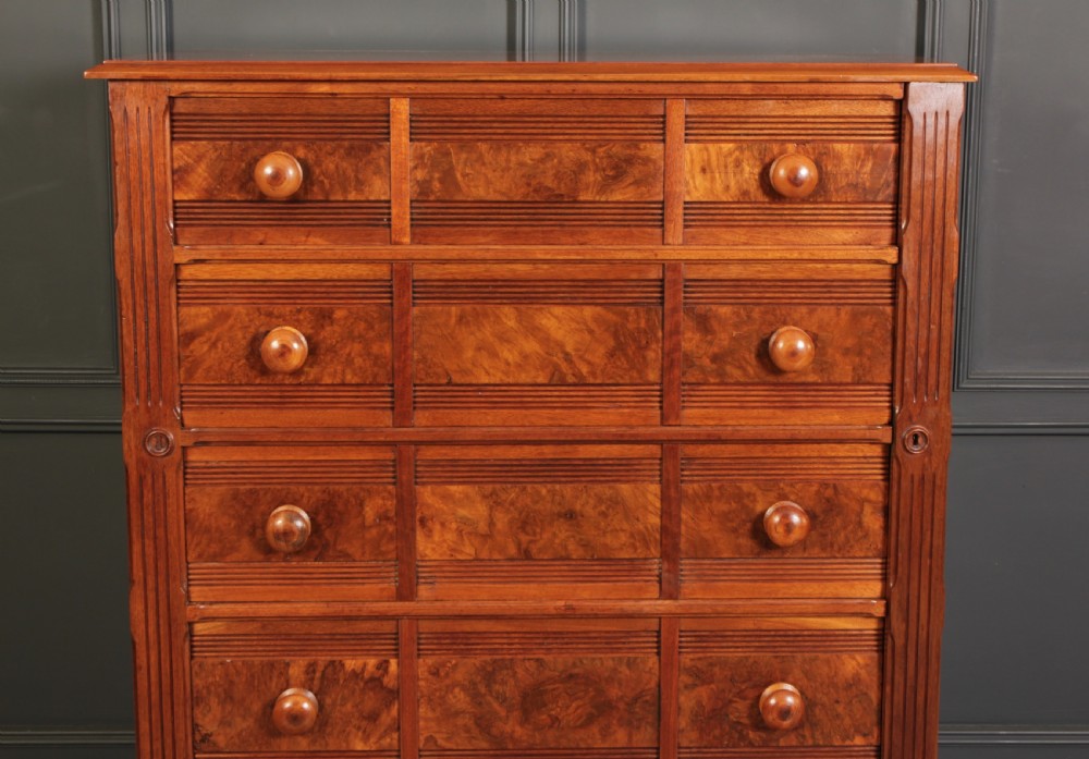 A tall late Victorian chest of drawers in warm burr walnut with multiple stacked drawers featuring turned wooden knobs and a moulded plinth base. View III