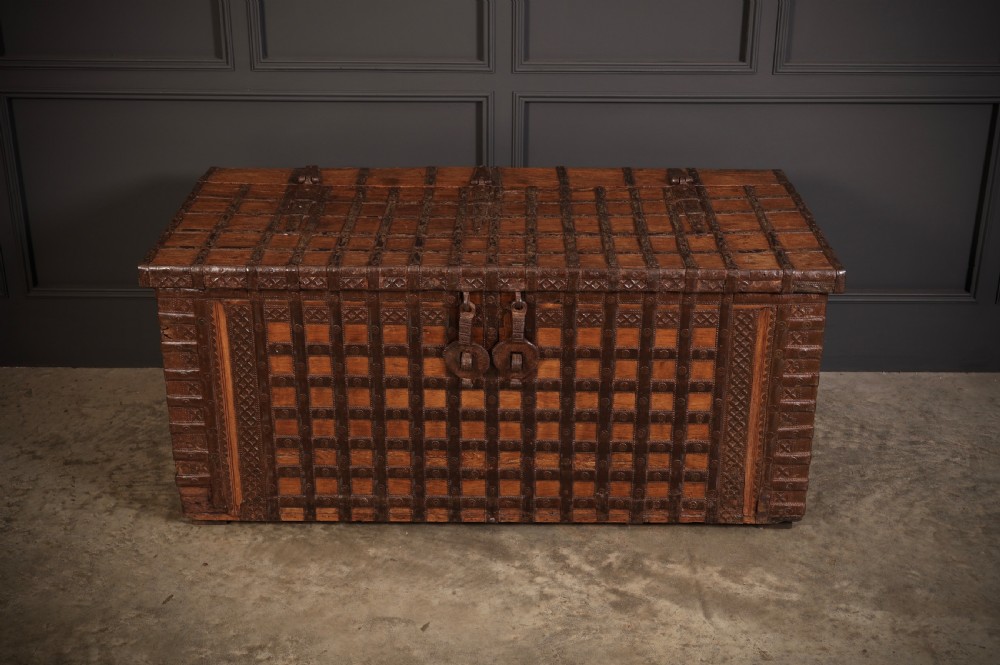A large rectangular brown hardwood trunk reinforced with a grid of iron straps and featuring heavy iron latches on the front. View III