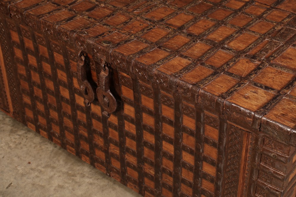 A large rectangular brown hardwood trunk reinforced with a grid of iron straps and featuring heavy iron latches on the front. View X
