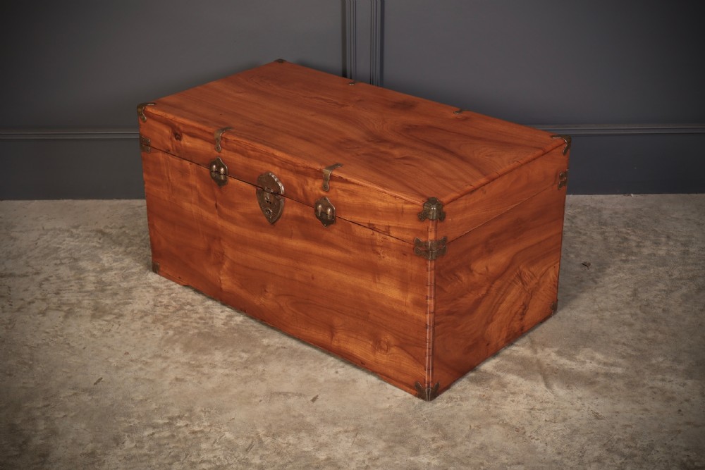 An antique warm amber brown camphor wood trunk featuring protective brass corner mounts, side handles, and a brass escutcheon. View VII