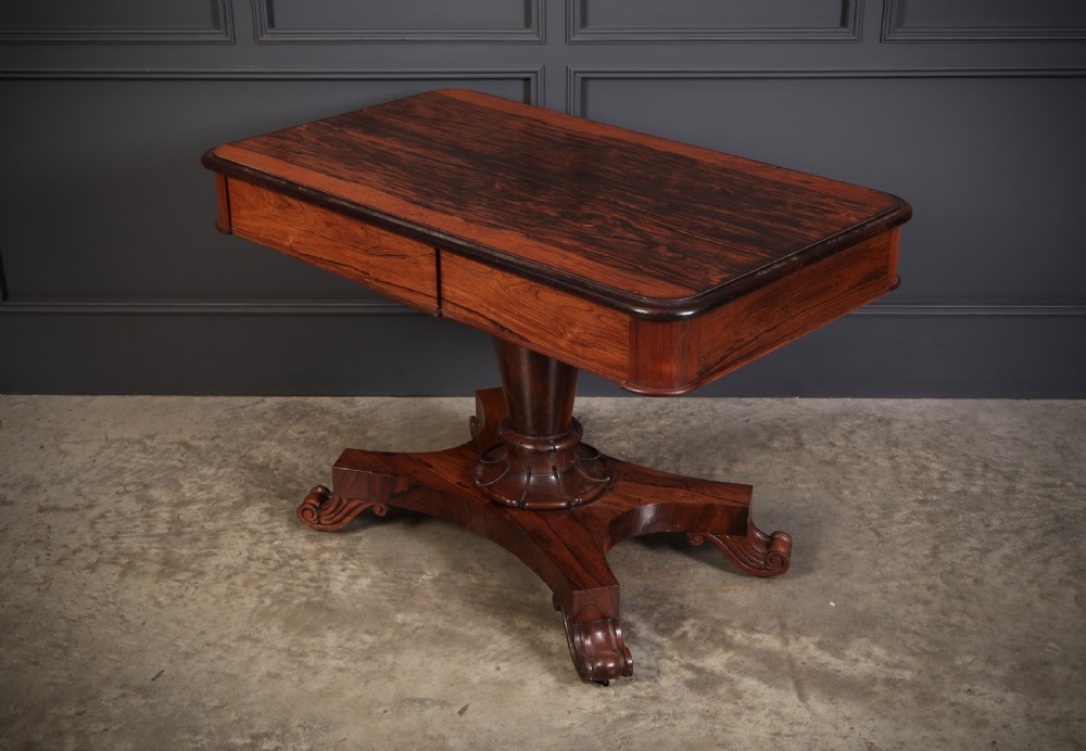 An antique rosewood library centre table featuring a rectangular figured top, two frieze drawers, a faceted pedestal column, and a quadform base with scroll feet. View VIII