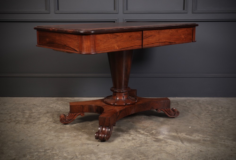 An antique rosewood library centre table featuring a rectangular figured top, two frieze drawers, a faceted pedestal column, and a quadform base with scroll feet. View XI