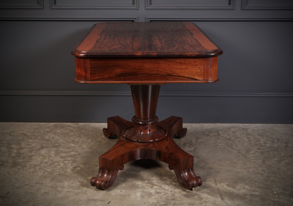 An antique rosewood library centre table featuring a rectangular figured top, two frieze drawers, a faceted pedestal column, and a quadform base with scroll feet. View XII