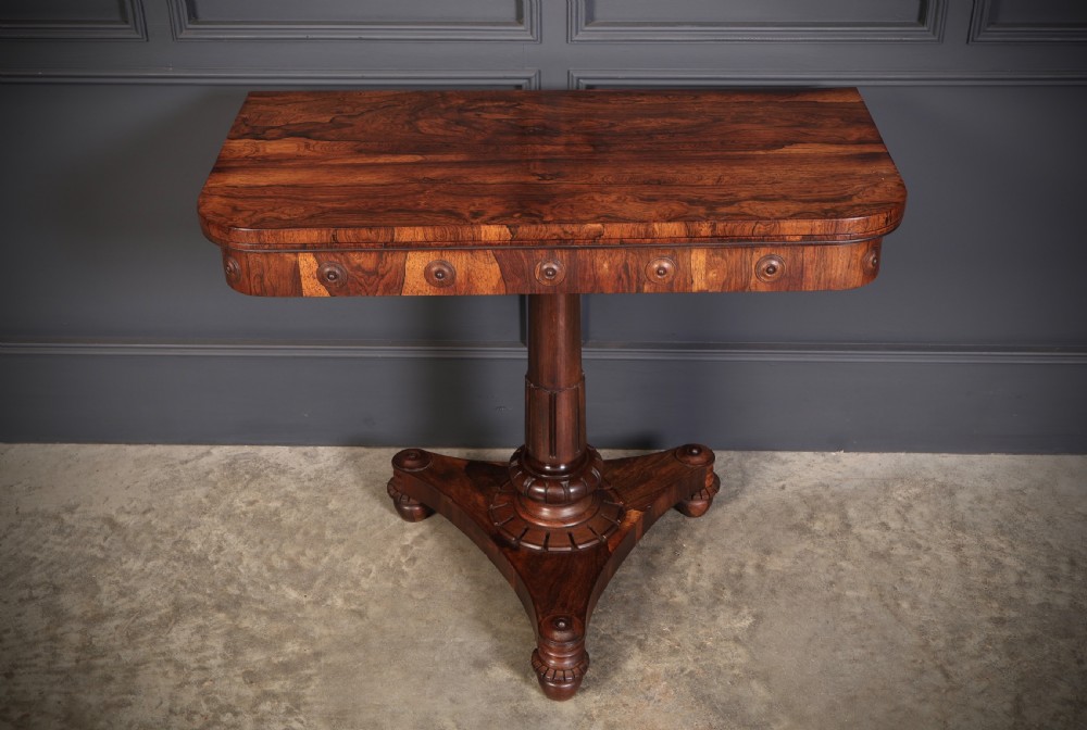 An antique Regency rosewood card table featuring a hinged rectangular top, rosette-decorated frieze, turned column, and triform pedestal base. View II