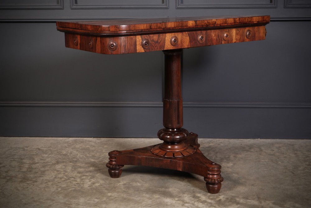 An antique Regency rosewood card table featuring a hinged rectangular top, rosette-decorated frieze, turned column, and triform pedestal base. View III