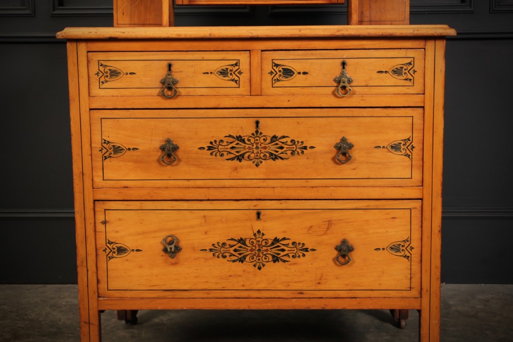 A satin birch dressing chest featuring an upper swivel mirror, small top drawers, larger lower drawers, and black stencilled decorative motifs. View III