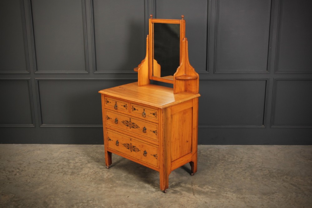 A satin birch dressing chest featuring an upper swivel mirror, small top drawers, larger lower drawers, and black stencilled decorative motifs. View VI