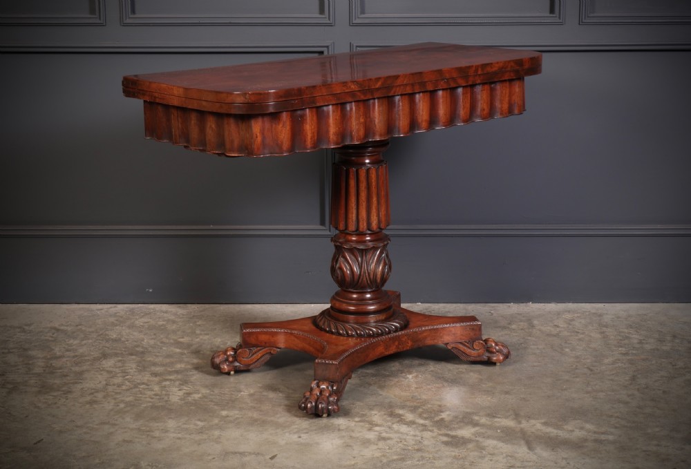 A Regency mahogany card table featuring a fold-over rectangular top, reeded apron, carved central pedestal, and quadripartite base with paw feet. View II