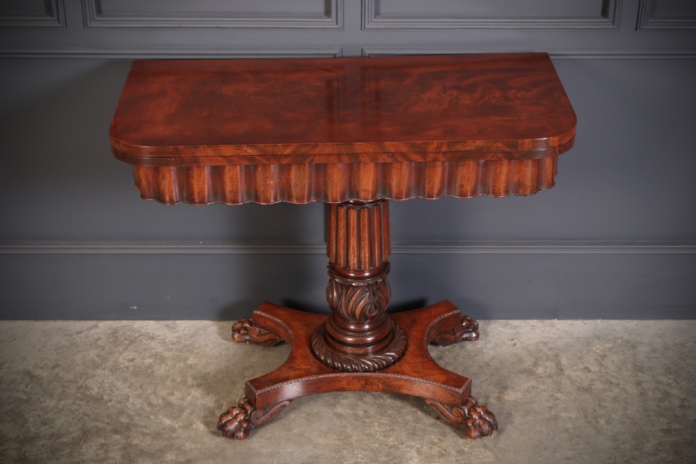 A Regency mahogany card table featuring a fold-over rectangular top, reeded apron, carved central pedestal, and quadripartite base with paw feet. View IV