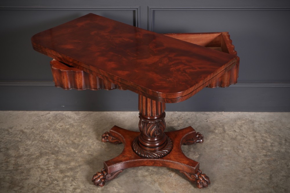A Regency mahogany card table featuring a fold-over rectangular top, reeded apron, carved central pedestal, and quadripartite base with paw feet. View IX