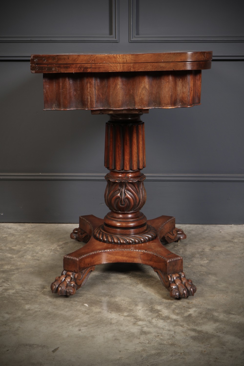 A Regency mahogany card table featuring a fold-over rectangular top, reeded apron, carved central pedestal, and quadripartite base with paw feet. View XVI