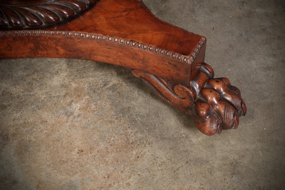 A Regency mahogany card table featuring a fold-over rectangular top, reeded apron, carved central pedestal, and quadripartite base with paw feet. View XVII