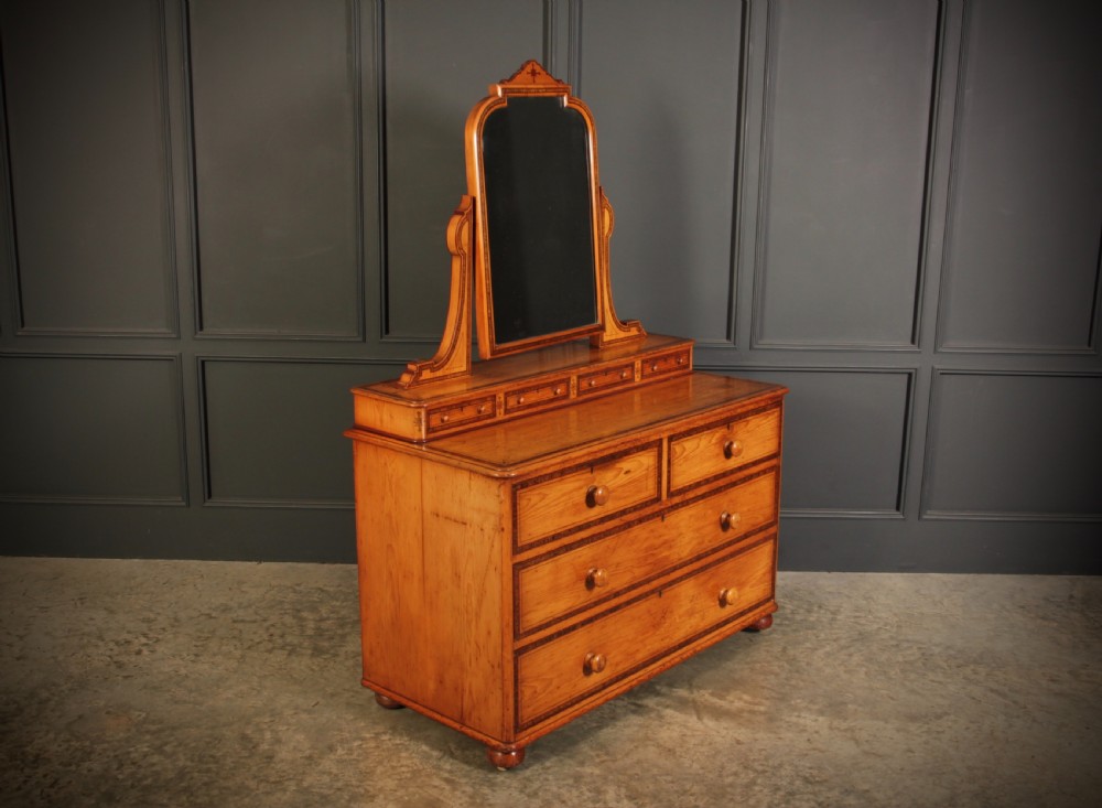 A Victorian pine dressing chest featuring dark stencilled border detailing, turned wooden handles, two short over two long drawers, small jewellery drawers, and an arched swivel mirror. View III