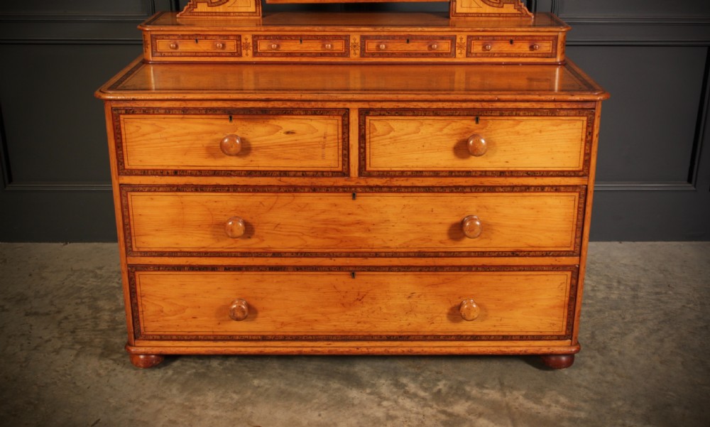 A Victorian pine dressing chest featuring dark stencilled border detailing, turned wooden handles, two short over two long drawers, small jewellery drawers, and an arched swivel mirror. View VII