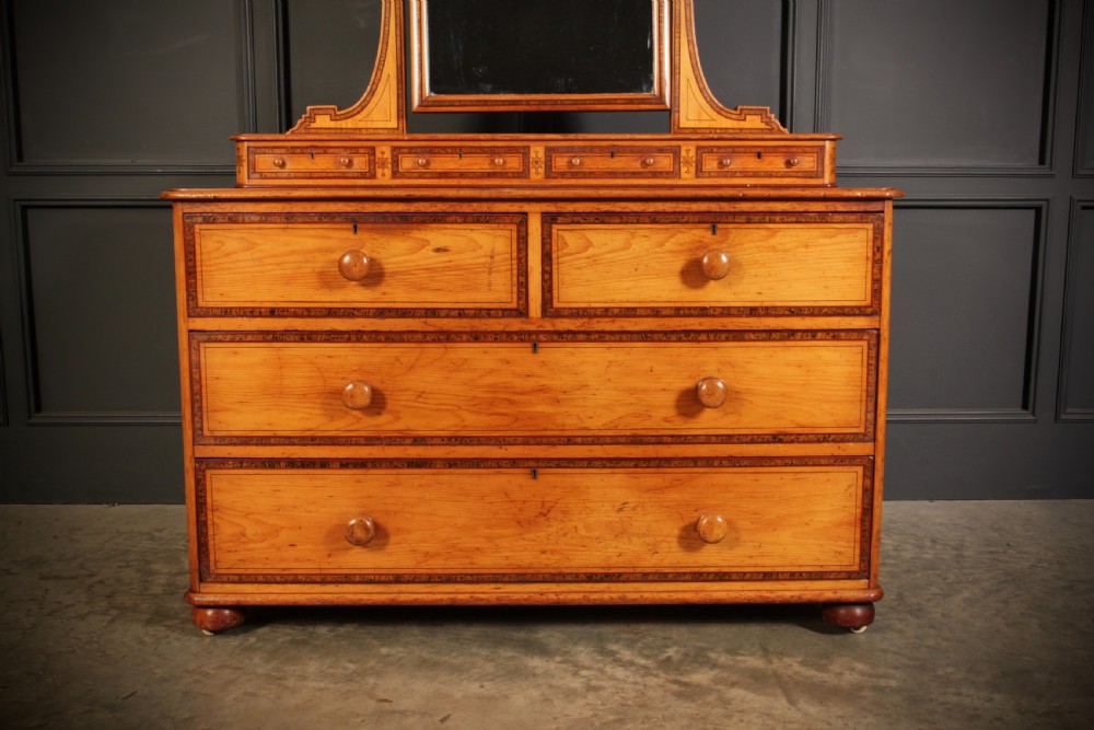 A Victorian pine dressing chest featuring dark stencilled border detailing, turned wooden handles, two short over two long drawers, small jewellery drawers, and an arched swivel mirror. View X