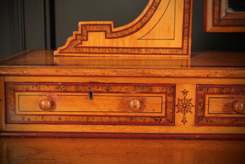 A Victorian pine dressing chest featuring dark stencilled border detailing, turned wooden handles, two short over two long drawers, small jewellery drawers, and an arched swivel mirror. View XIV