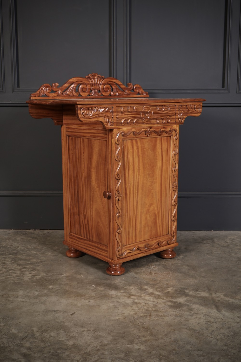 A carved satinwood Anglo-Indian side cabinet featuring a scroll-carved gallery back, panelled door, and turned feet. View II