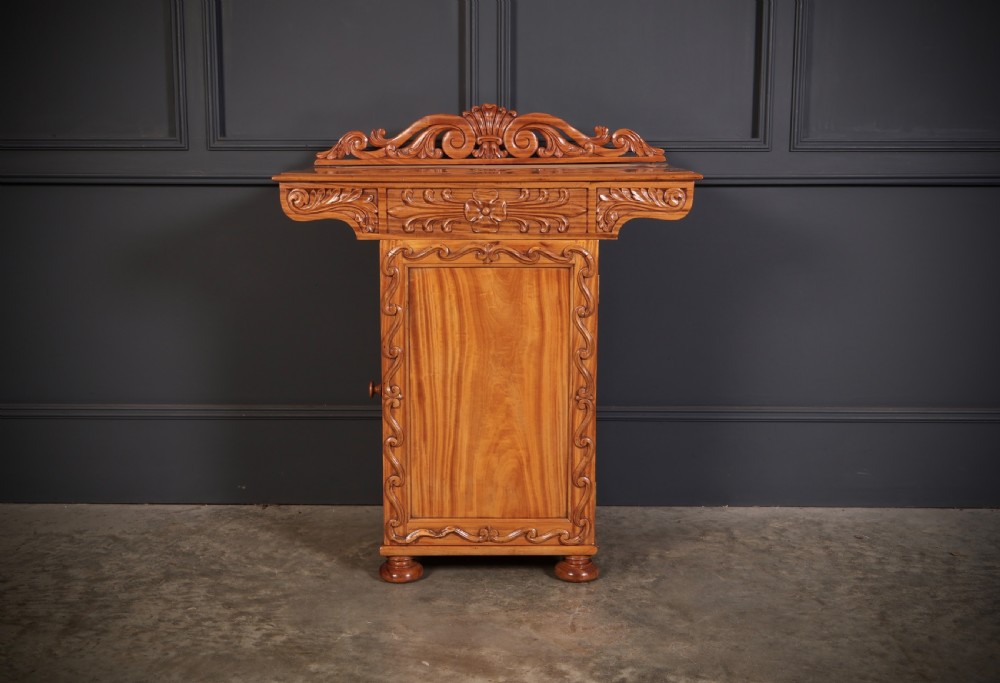 A carved satinwood Anglo-Indian side cabinet featuring a scroll-carved gallery back, panelled door, and turned feet. View V