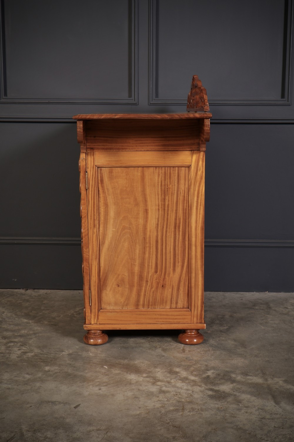 A carved satinwood Anglo-Indian side cabinet featuring a scroll-carved gallery back, panelled door, and turned feet. View VII