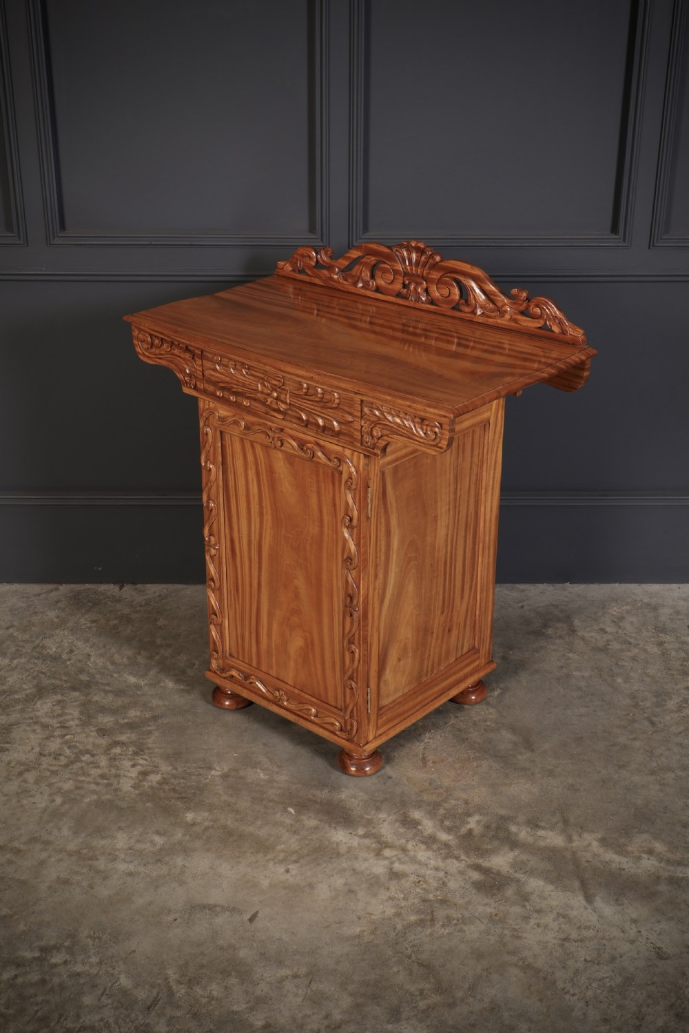 A carved satinwood Anglo-Indian side cabinet featuring a scroll-carved gallery back, panelled door, and turned feet. View IX