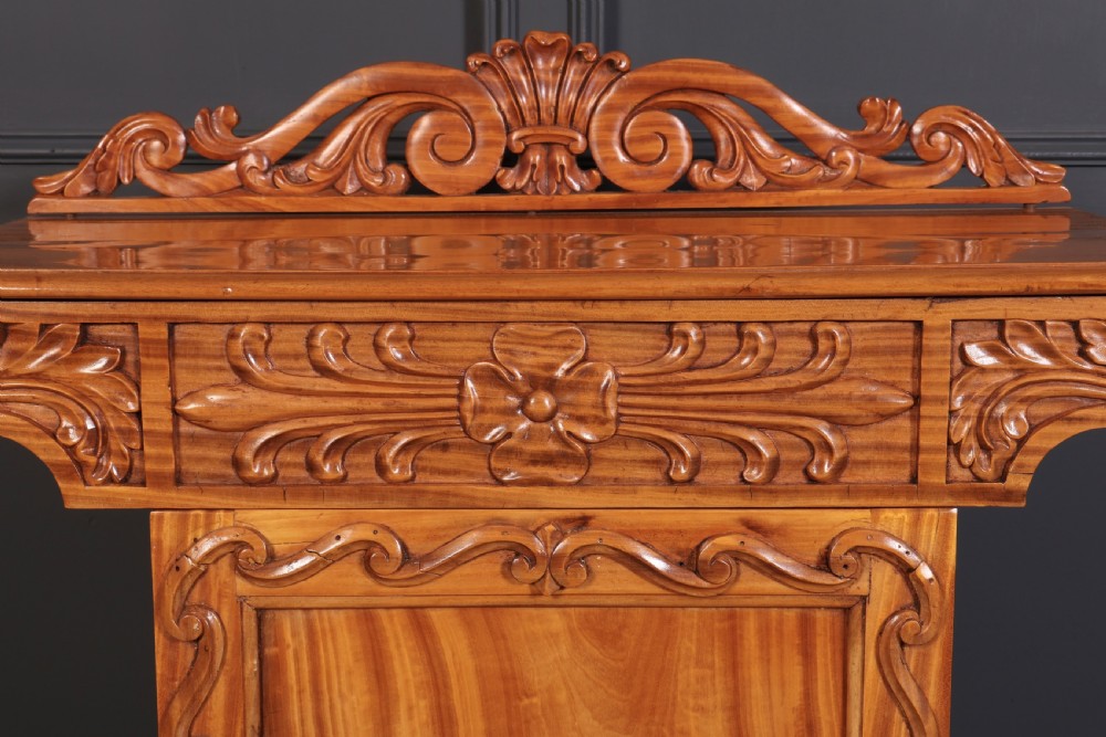 A carved satinwood Anglo-Indian side cabinet featuring a scroll-carved gallery back, panelled door, and turned feet. View XI