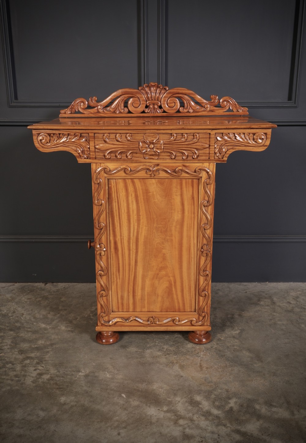 A carved satinwood Anglo-Indian side cabinet featuring a scroll-carved gallery back, panelled door, and turned feet. View XIII