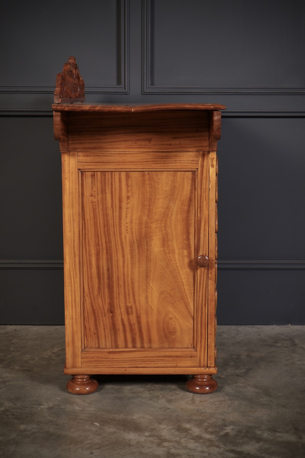 A carved satinwood Anglo-Indian side cabinet featuring a scroll-carved gallery back, panelled door, and turned feet. View XV