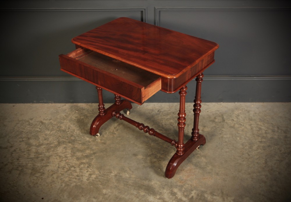 An early Victorian polished mahogany side table featuring turned dual pedestal legs, a central turned stretcher, and curved feet on castors. View XIV