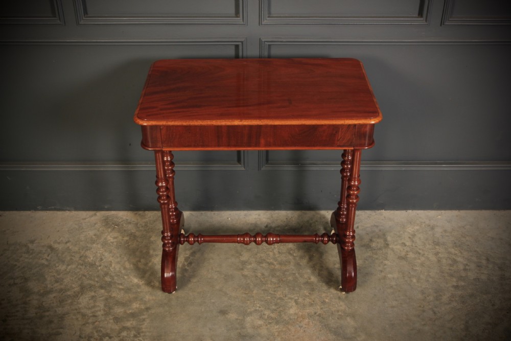 An early Victorian polished mahogany side table featuring turned dual pedestal legs, a central turned stretcher, and curved feet on castors. View VI