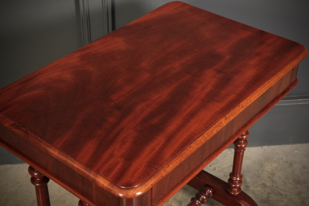 An early Victorian polished mahogany side table featuring turned dual pedestal legs, a central turned stretcher, and curved feet on castors. View VIII