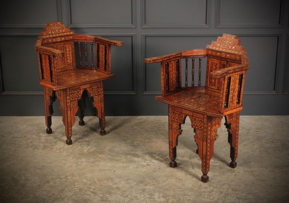 A pair of Syrian Moorish wooden armchairs featuring geometric bone and mother-of-pearl marquetry inlay and turned spindles.