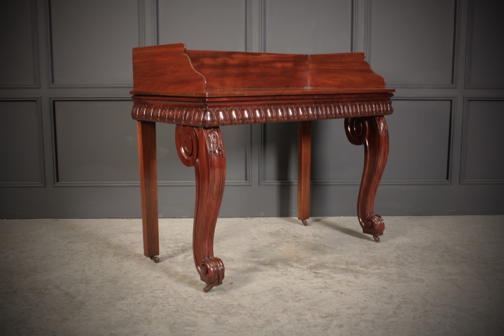 A William IV mahogany console table featuring a raised gallery back, gadrooned edge detailing, and bold S-scroll front legs on brass castors. View II
