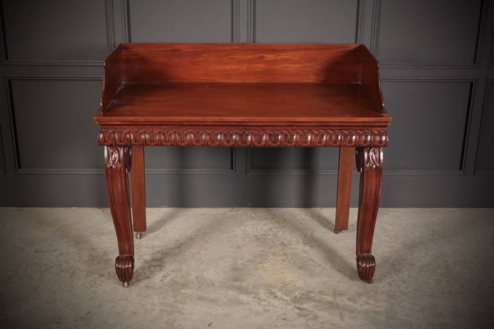 A William IV mahogany console table featuring a raised gallery back, gadrooned edge detailing, and bold S-scroll front legs on brass castors. View III