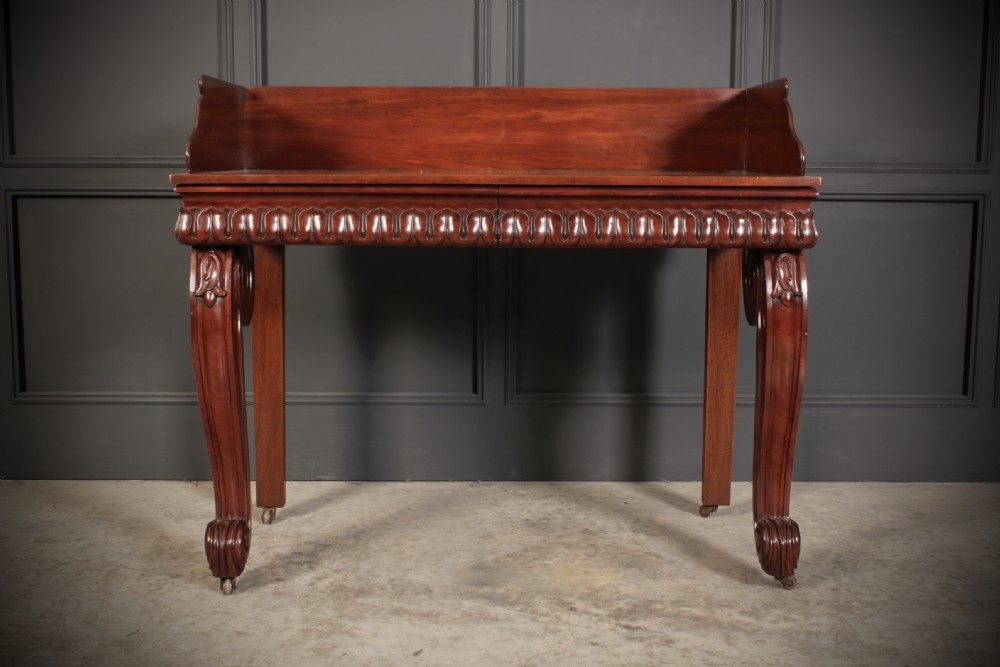 A William IV mahogany console table featuring a raised gallery back, gadrooned edge detailing, and bold S-scroll front legs on brass castors. View V