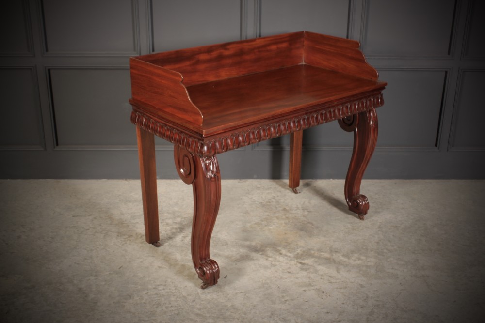A William IV mahogany console table featuring a raised gallery back, gadrooned edge detailing, and bold S-scroll front legs on brass castors. View VI
